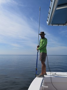 FSUCML marine technician Chris Matechik holds the light sensor at different depths in the water column while the data is transmitted and recorded by a datalogger
