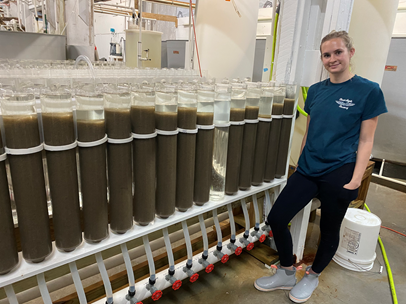 Morgan Hawkins next to high density oyster seed bottles